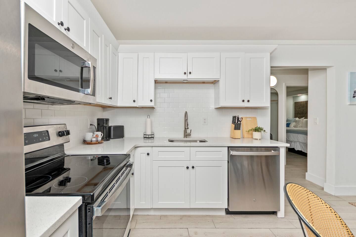 Bright white modern kitchen with stainless steel appliances, white cabinets, and a tiled backsplash