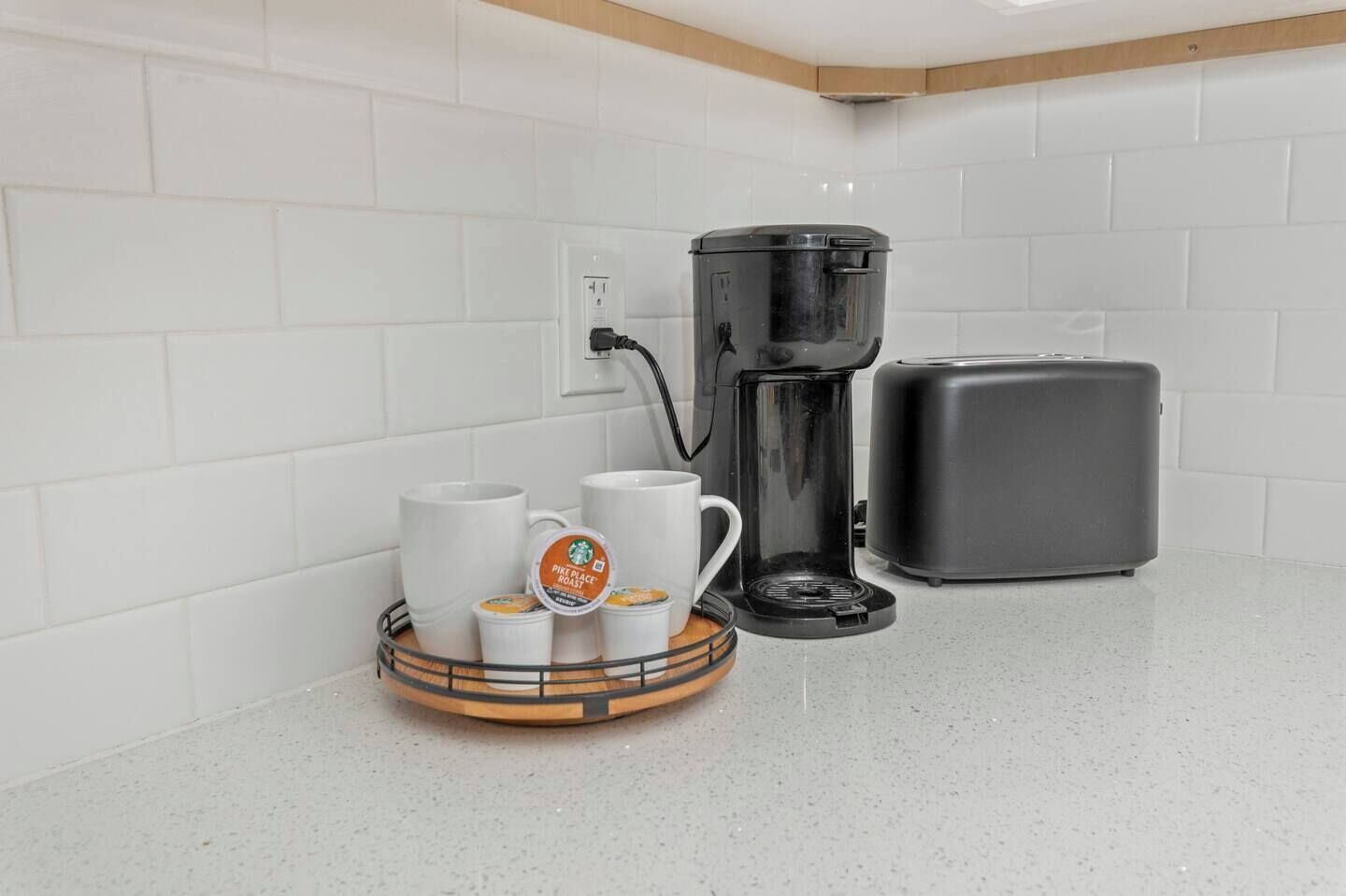 Coffee maker, mug, and small tray on a white kitchen countertop beside a toaster.