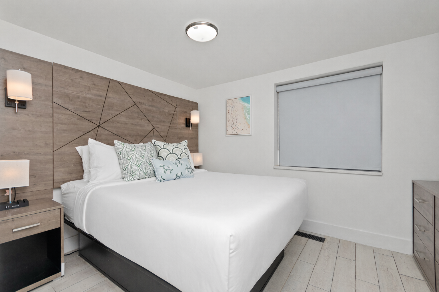 Modern bedroom with a large bed, gray wood accent wall, and closed window blind