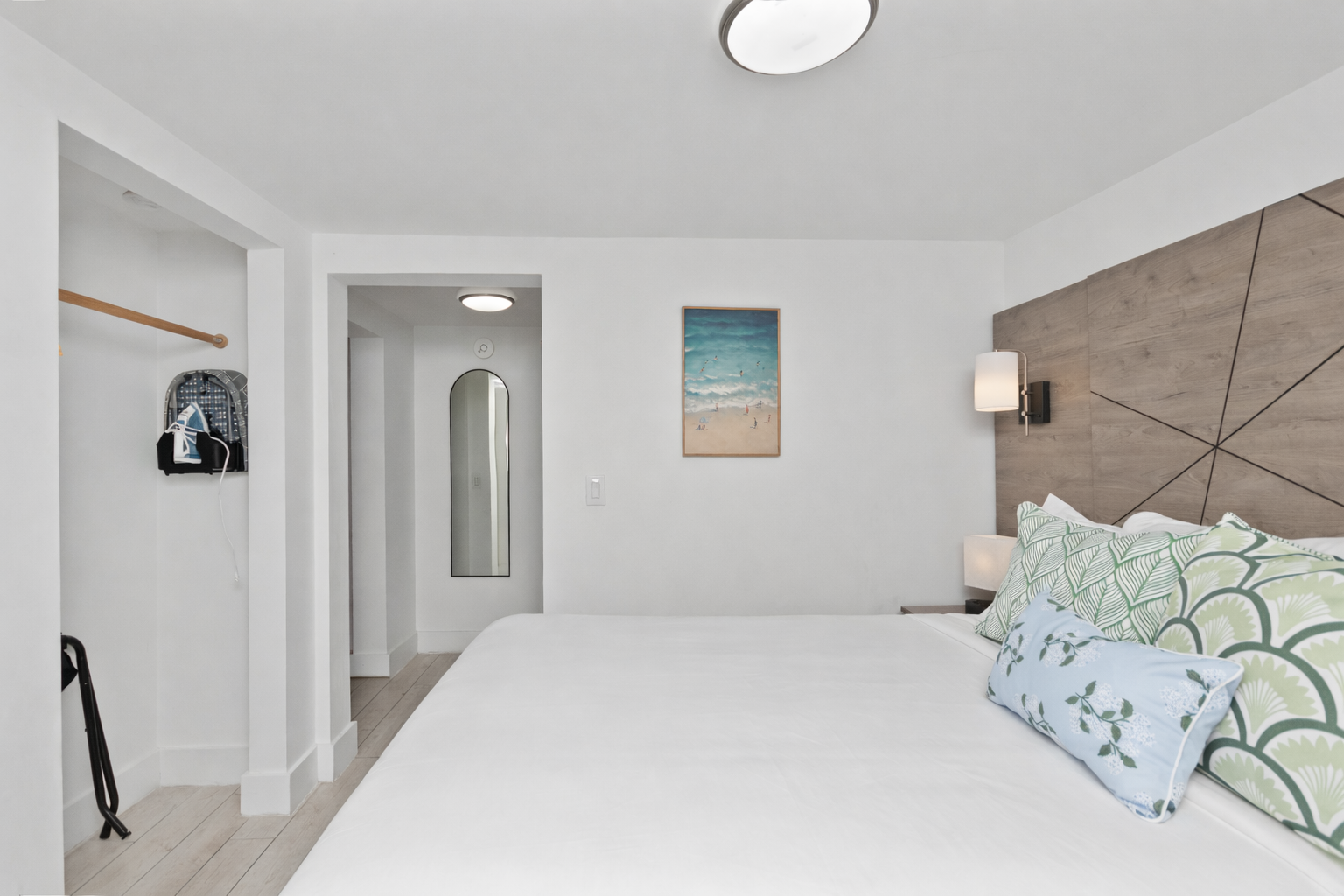 Bright minimalist bedroom with white walls, a tufted headboard, and a wall art print.