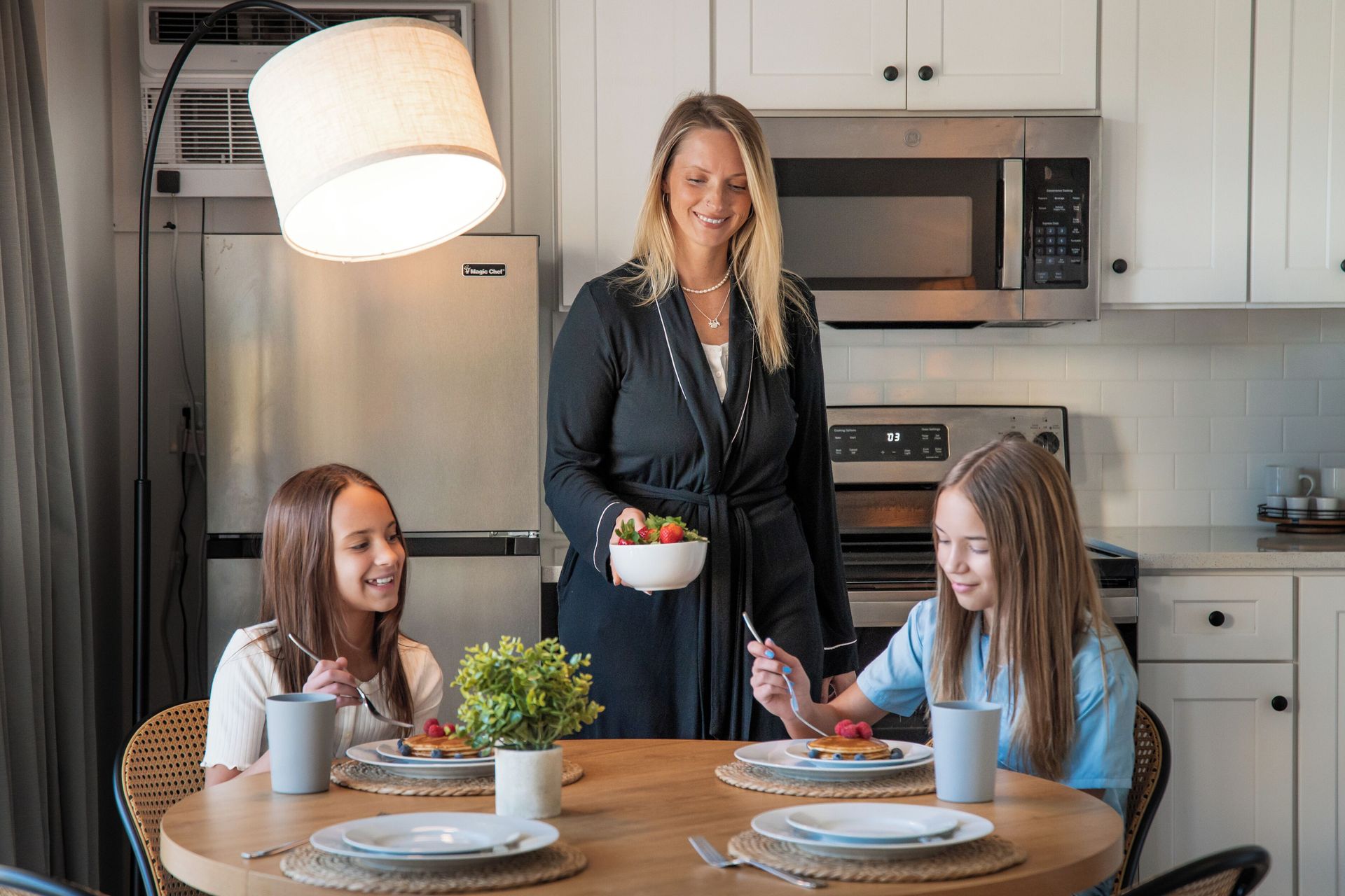 Woman serving breakfast to two girls at a kitchen table