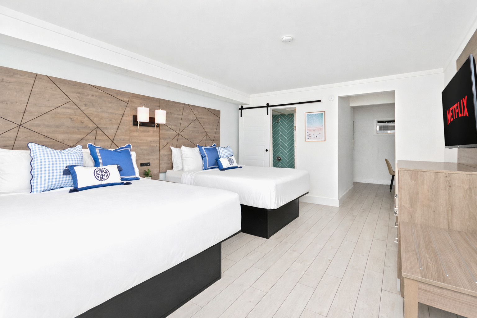 Modern hotel room with two twin beds, white walls, wood accents, and a TV on the right