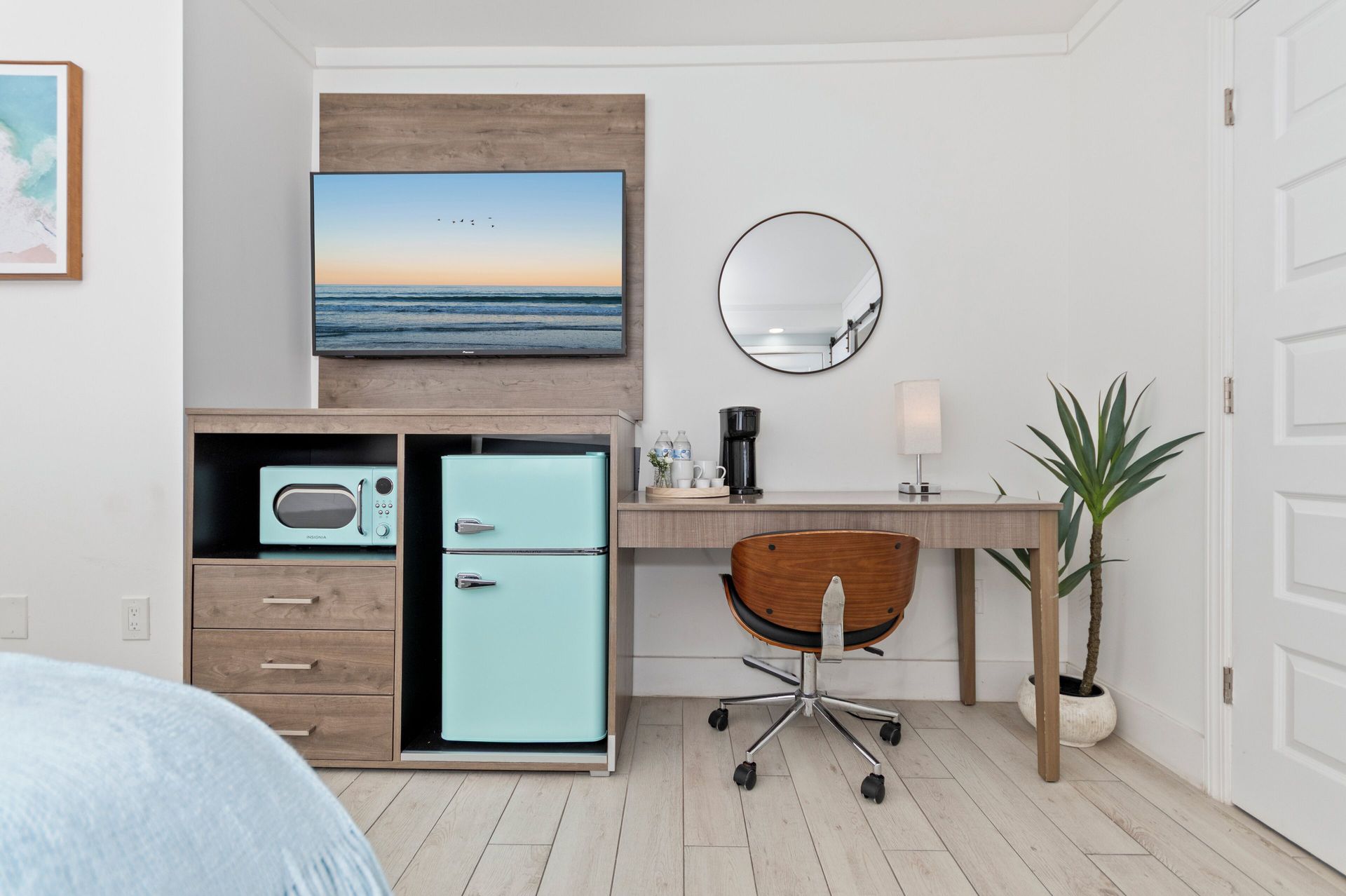Stylish bedroom corner with mint mini fridge, desk, chair, wall art, and beach photo above cabinet