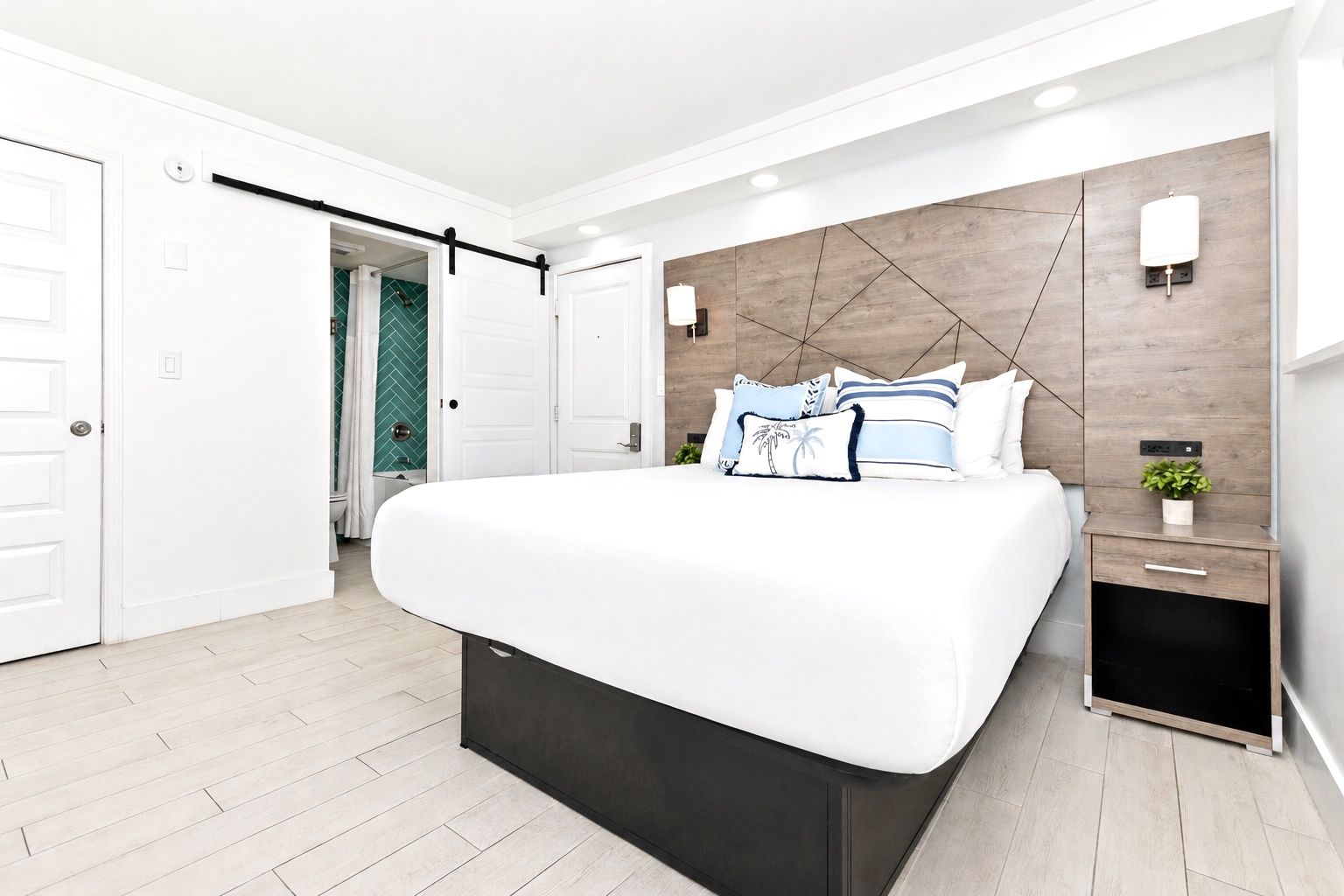 Bedroom with a bed, nightstand, and sliding door to a bathroom. Light blue and white decor.