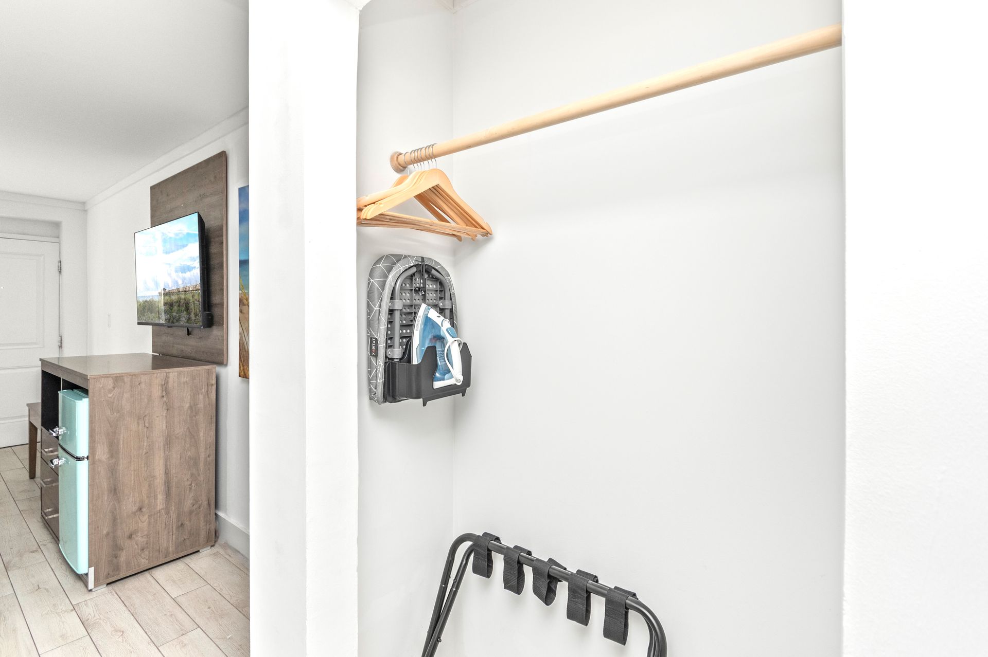 Walk-in closet with white walls, wooden hanging rod, metal shelf, and closet organizer by a bedroom doorway