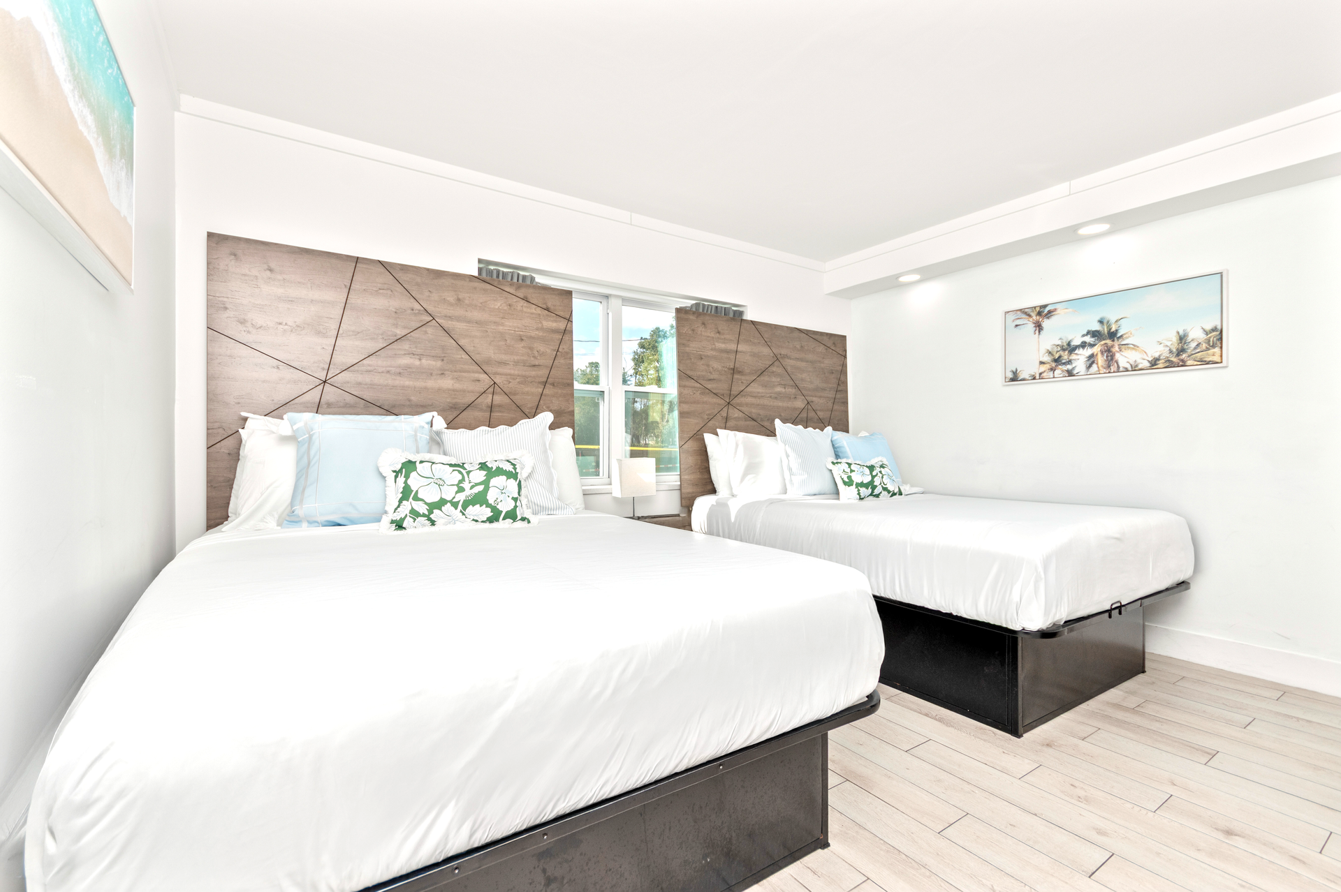 Bright bedroom with two white beds, tufted headboards, and light wood flooring