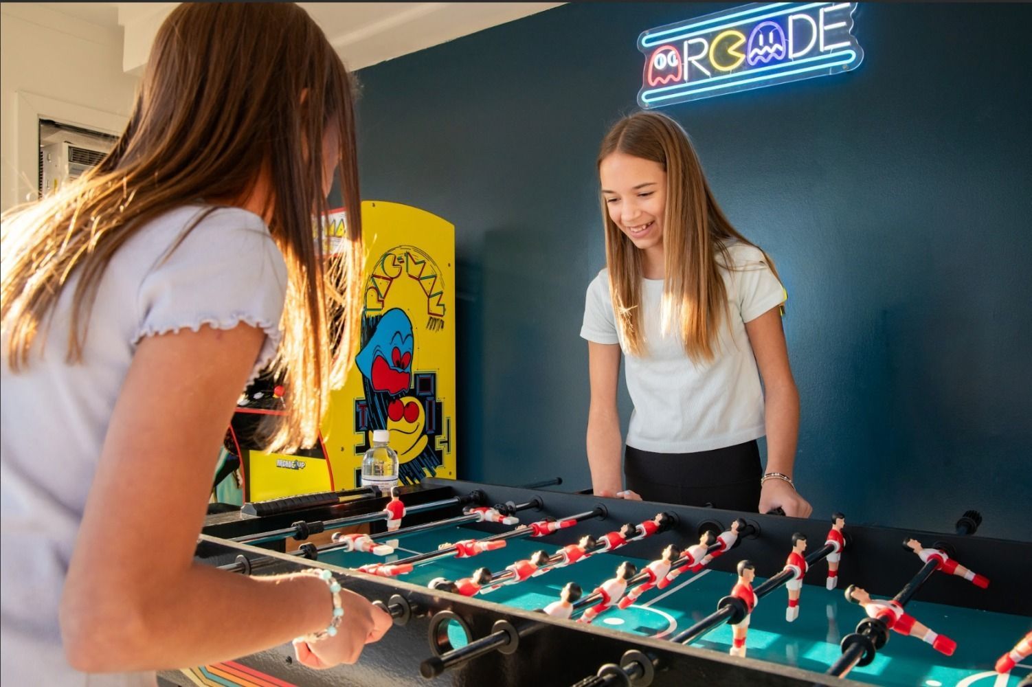 Two people playing foosball in a game room with an