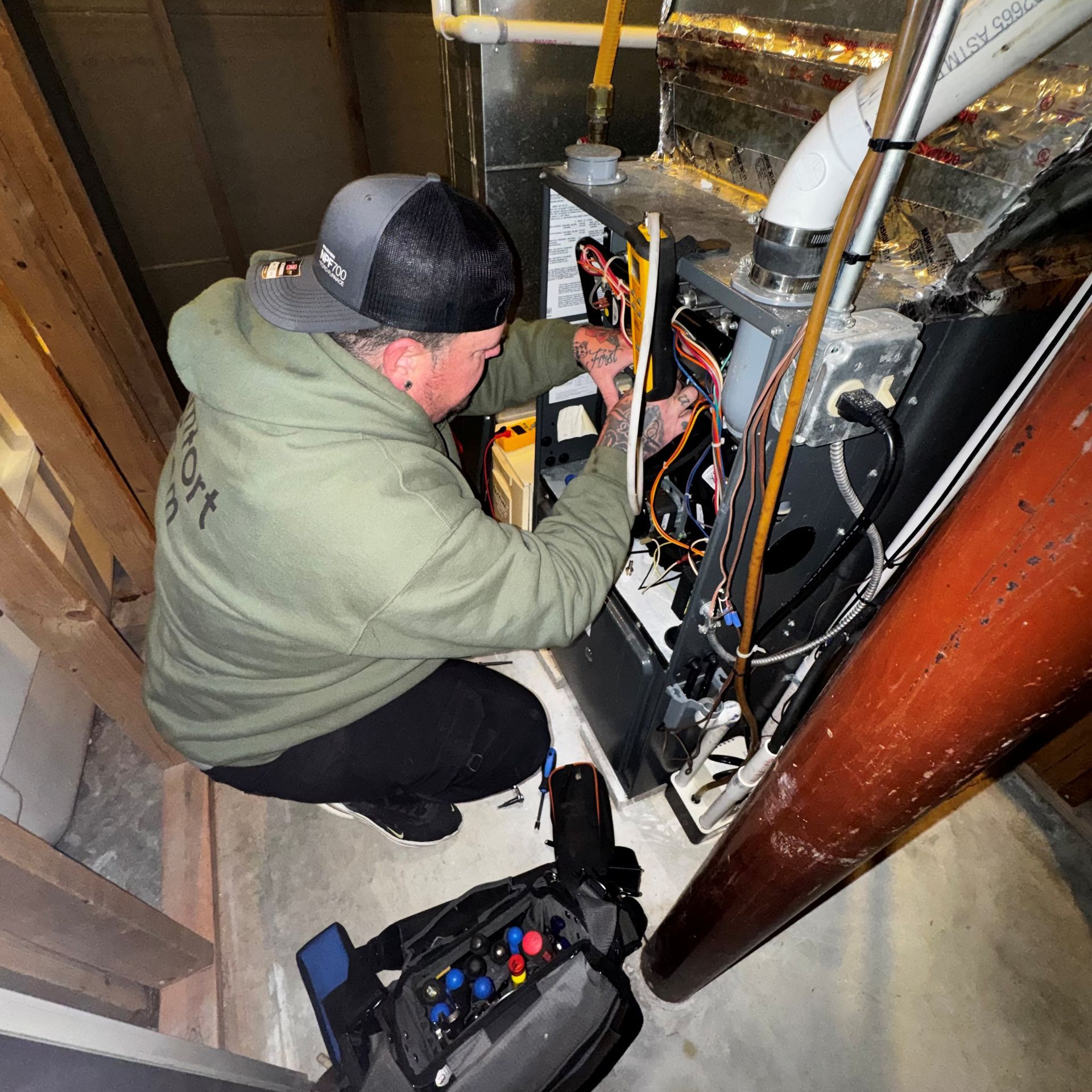 HVAC technician in safety gear inspects rooftop air conditioning units on a cloudy day.