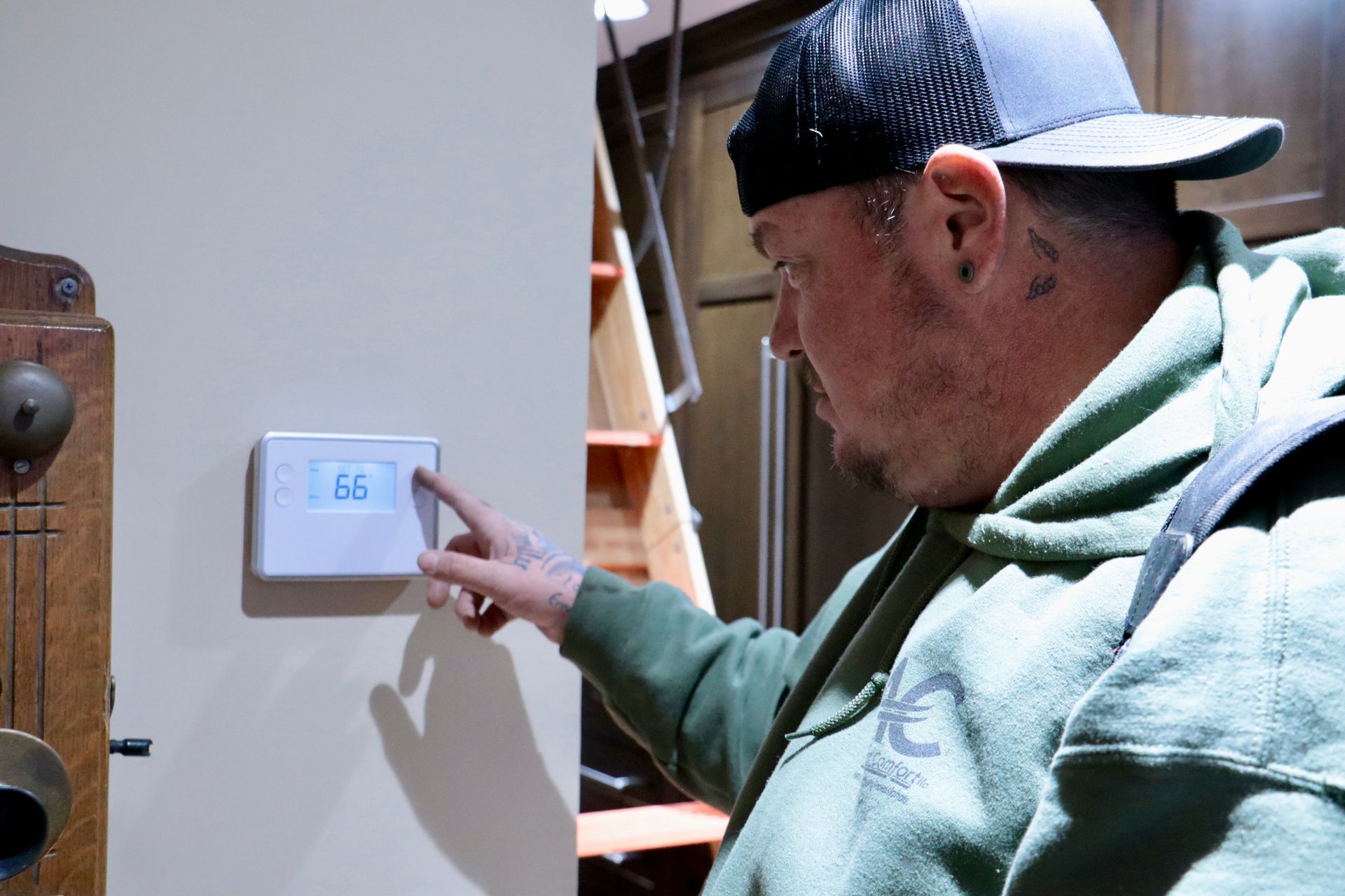 White smart thermostat displaying 20°C on a gray wall in a house.