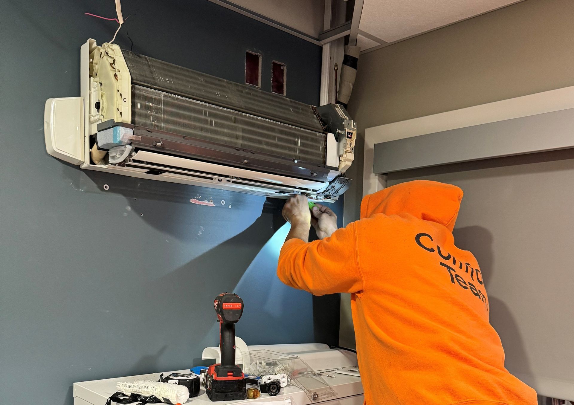 Plumber using a wrench on a steaming radiator in a workshop.