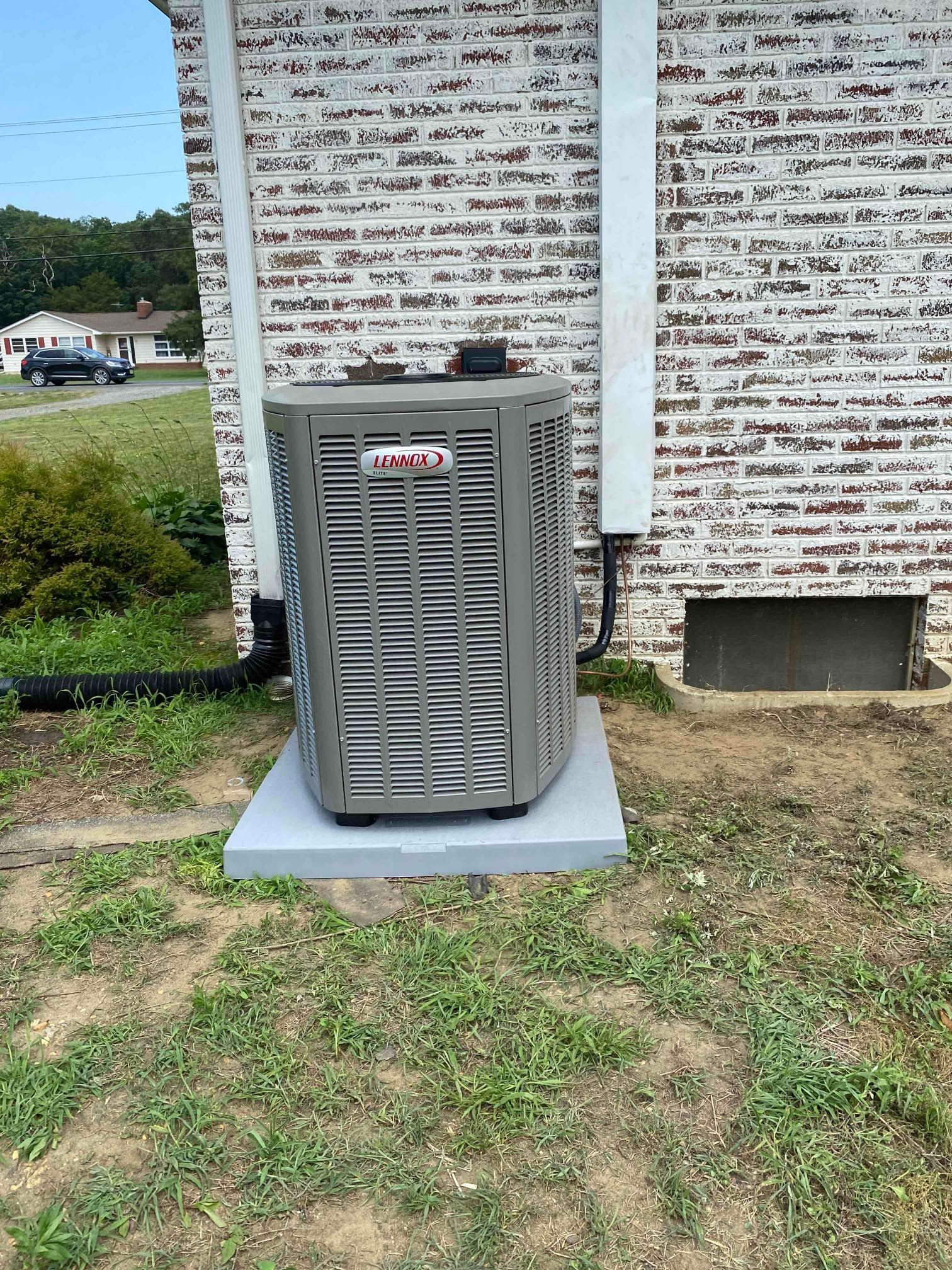 Air conditioning units and vent pipe installed outside a brick building.