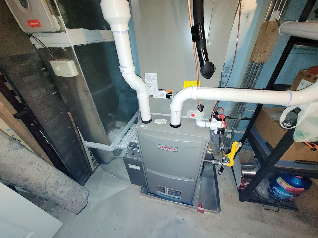Furnace installation with white PVC pipes, gas line, in a basement setting.
