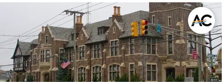 Brick building with American flag, traffic light, and power lines against a gray sky.