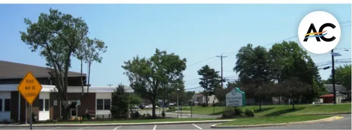 Street view with trees, buildings, a sign, and a blue sky.