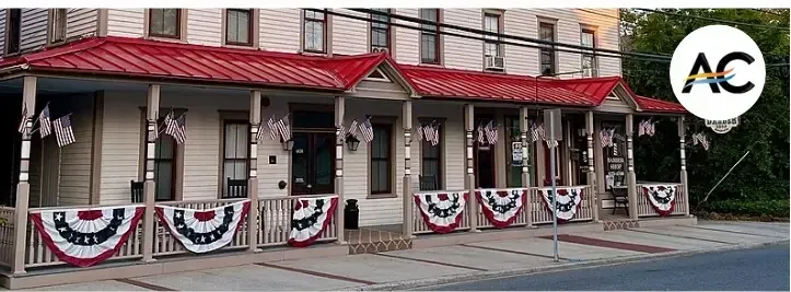 Row of shops with red roofs and patriotic bunting, decorated with US flags.