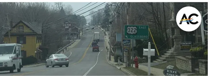 Road scene with cars, signs, and houses. Green exit sign for PA 322 East to Doylestown.