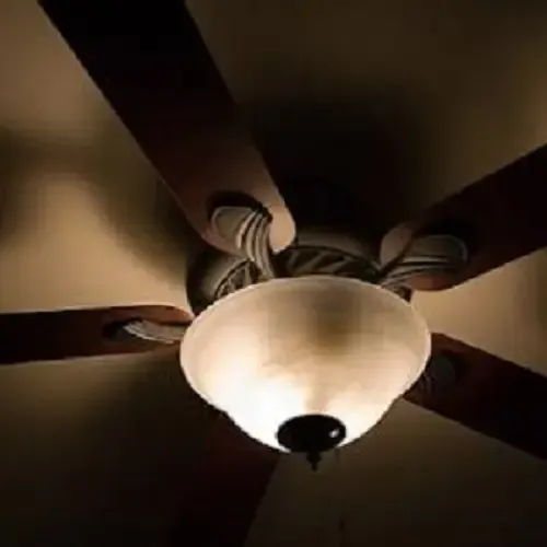 A ceiling fan with a light hanging from it in a dark room.