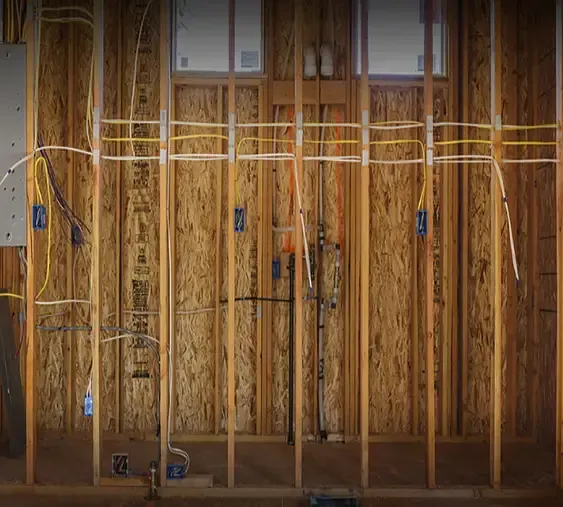 A wooden wall with electrical wires coming out of it.