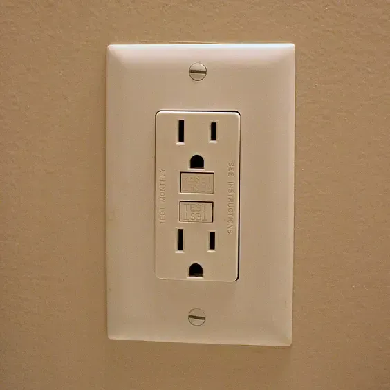 A white electrical outlet on a brown wall.