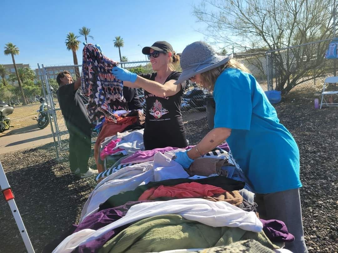 Two women are standing next to a pile of clothes.