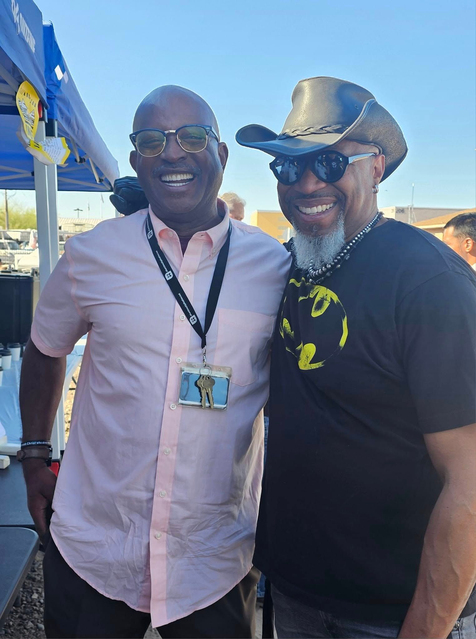 Two men are posing for a picture together and one of them is wearing a cowboy hat.