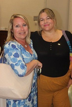 two women are posing for a picture together while standing next to each other .