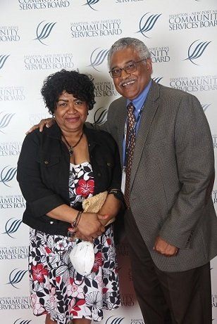 a man and a woman are posing for a picture in front of a wall .