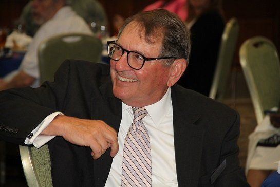 a man in a suit and tie is smiling while sitting at a table