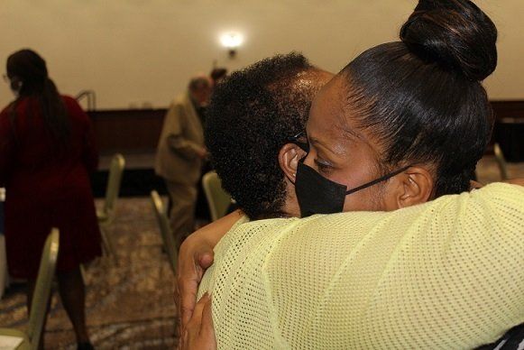 a woman wearing a mask is hugging a man .
