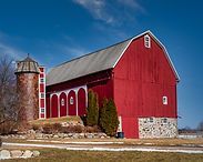 Red barn with silos on a farm under a blue sky