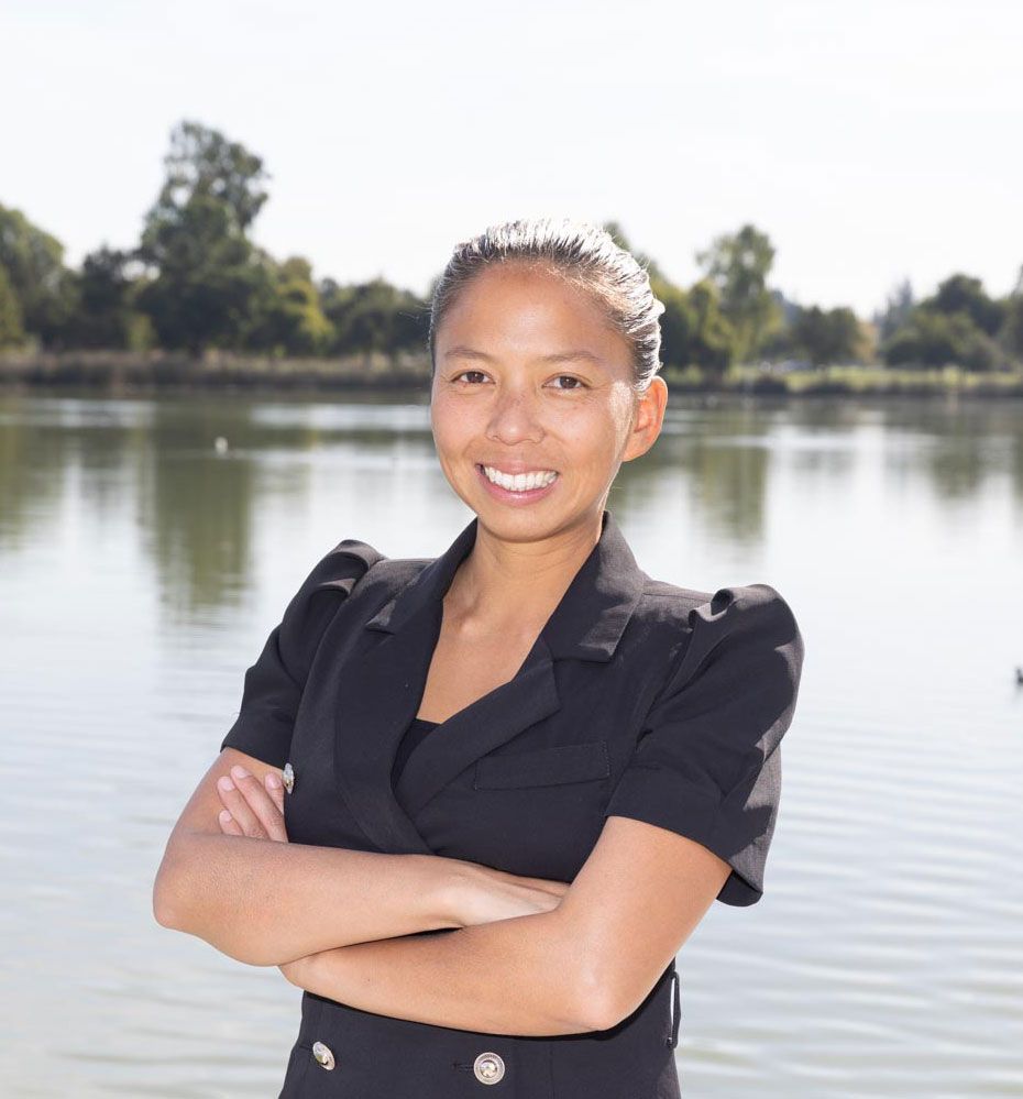 A woman is standing in front of a lake with her arms crossed