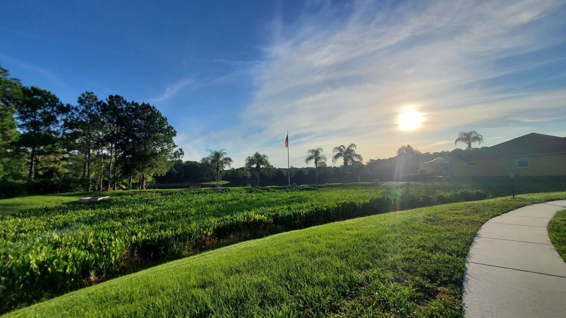 The sun is shining through the clouds over a grassy field.