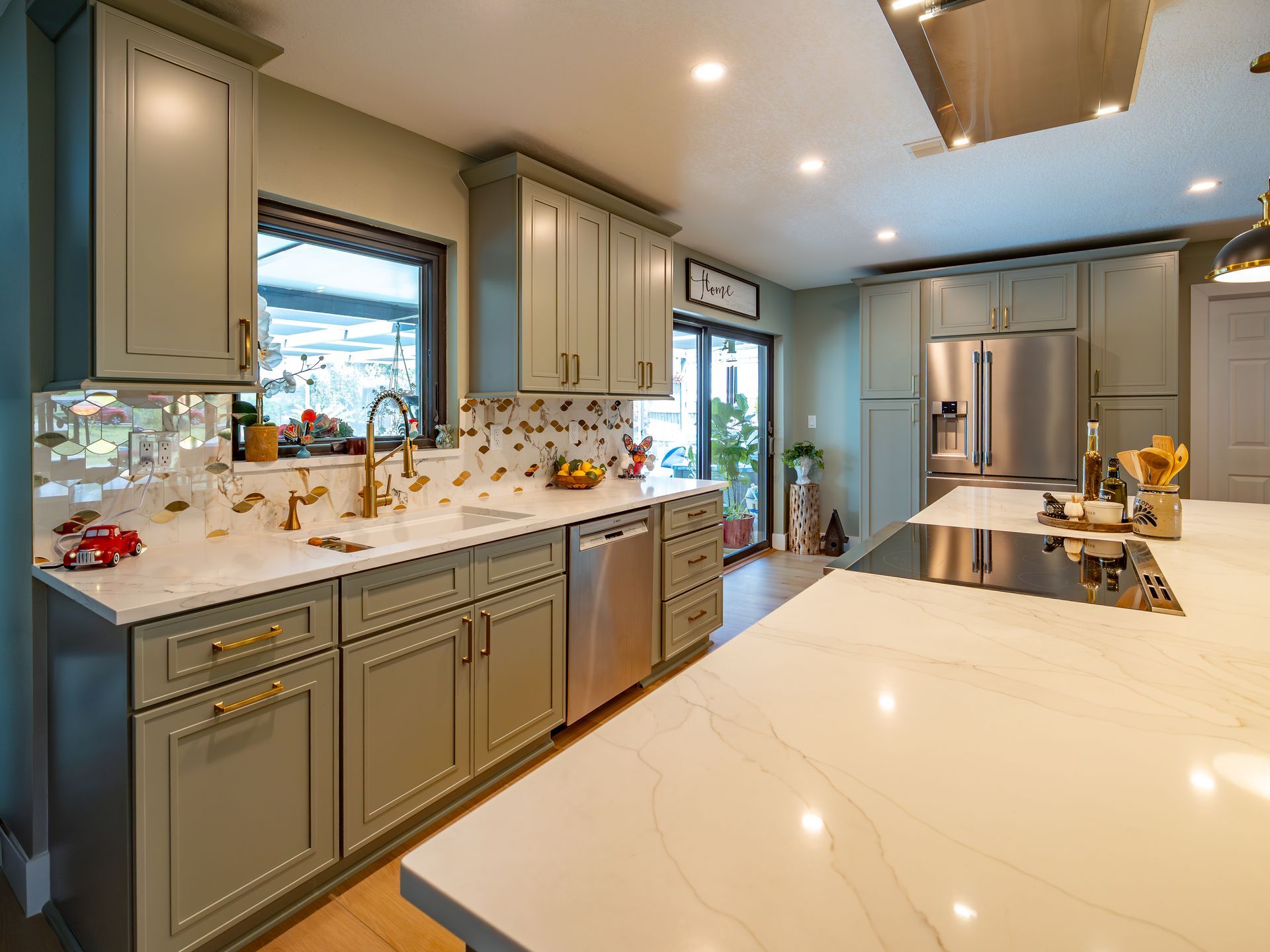 Green kitchen with white countertops, stainless steel appliances, and a large island.