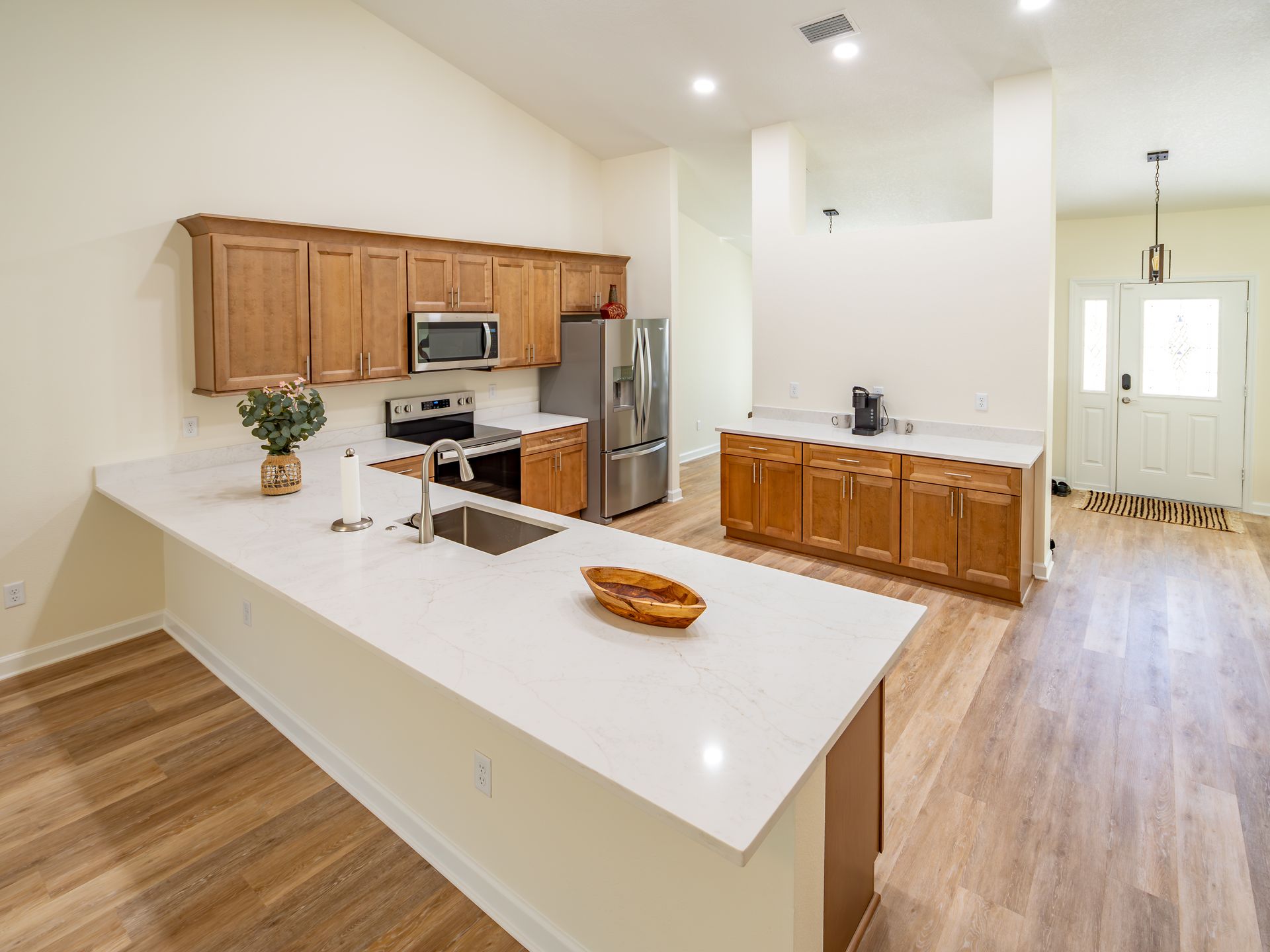 Spacious kitchen with wood cabinets, white countertops, stainless steel appliances, and a large island.