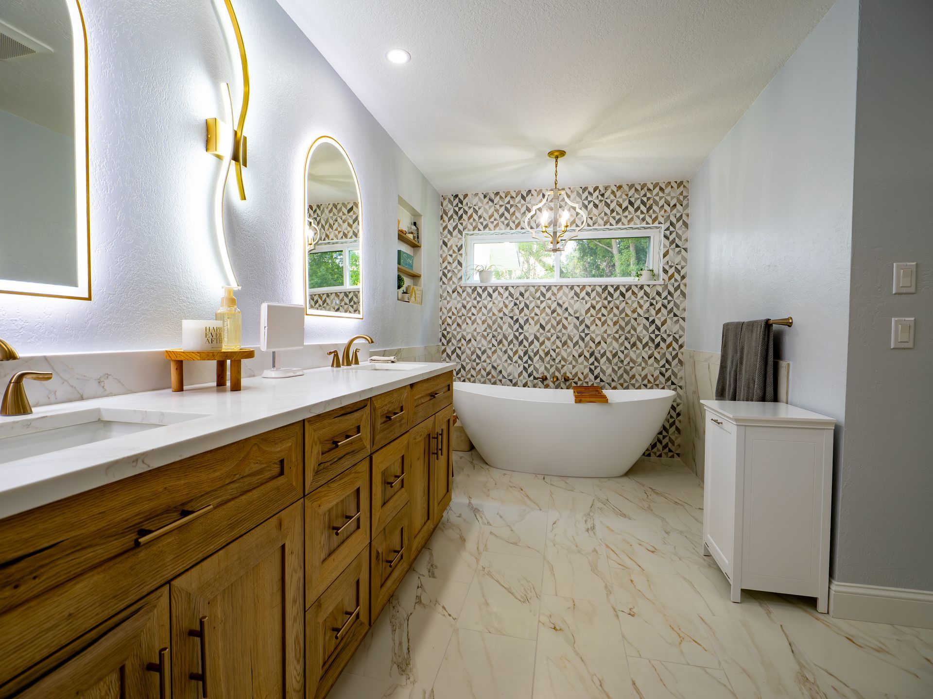 Modern bathroom with wooden vanity, white tub, and gold accents.