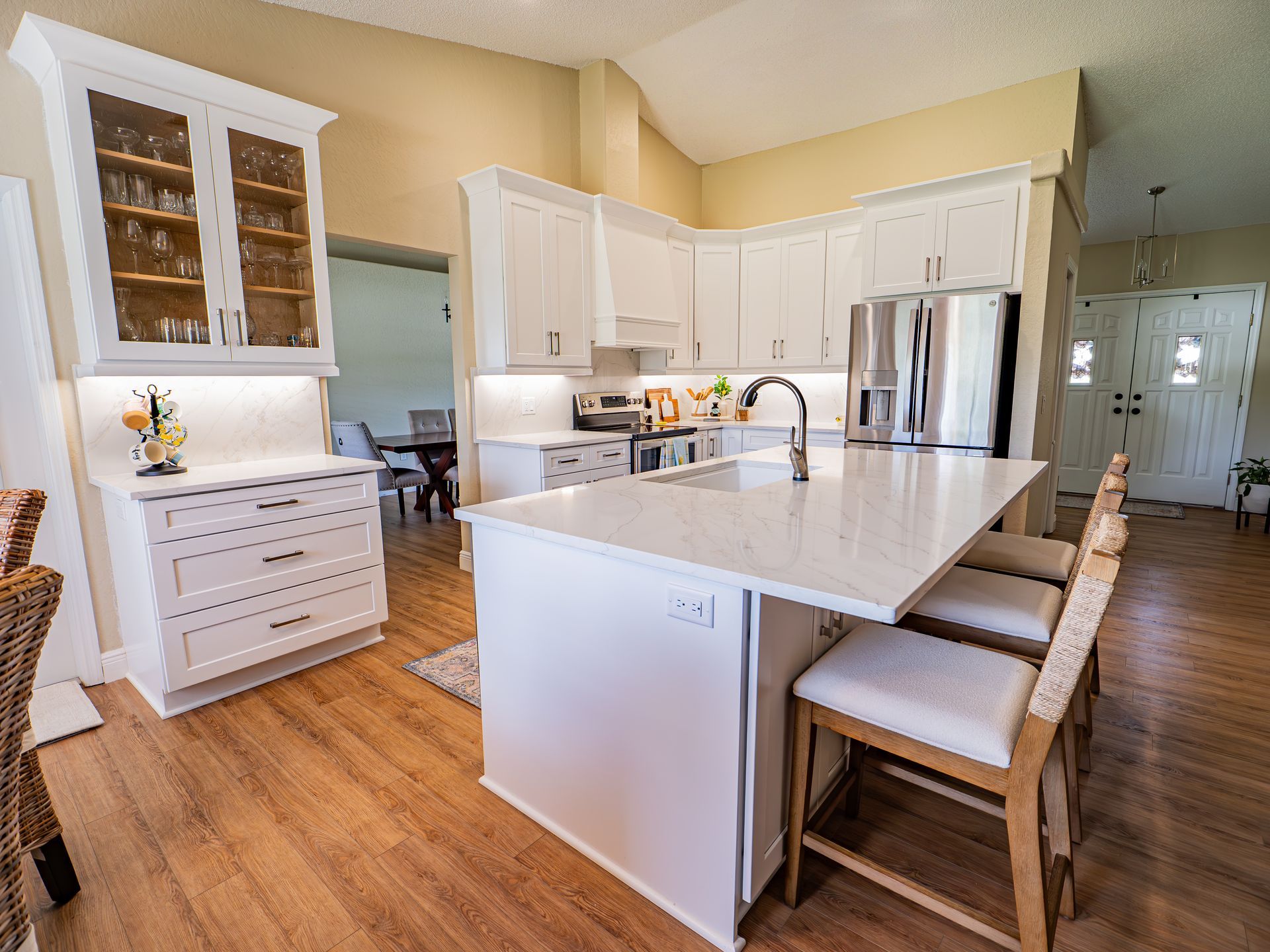 Bright white kitchen with island, stainless steel appliances, and light wood floors.