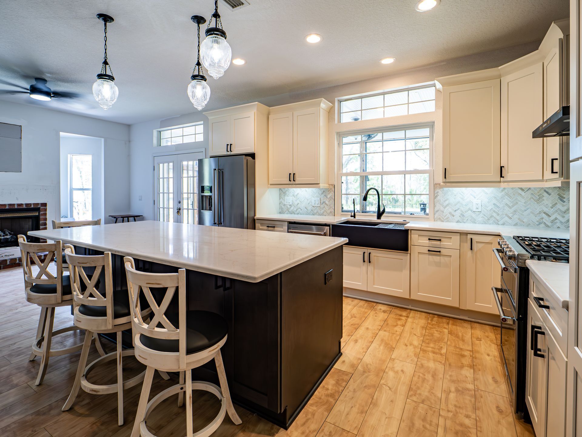 Modern kitchen with a large island, white cabinets, and wood floors.