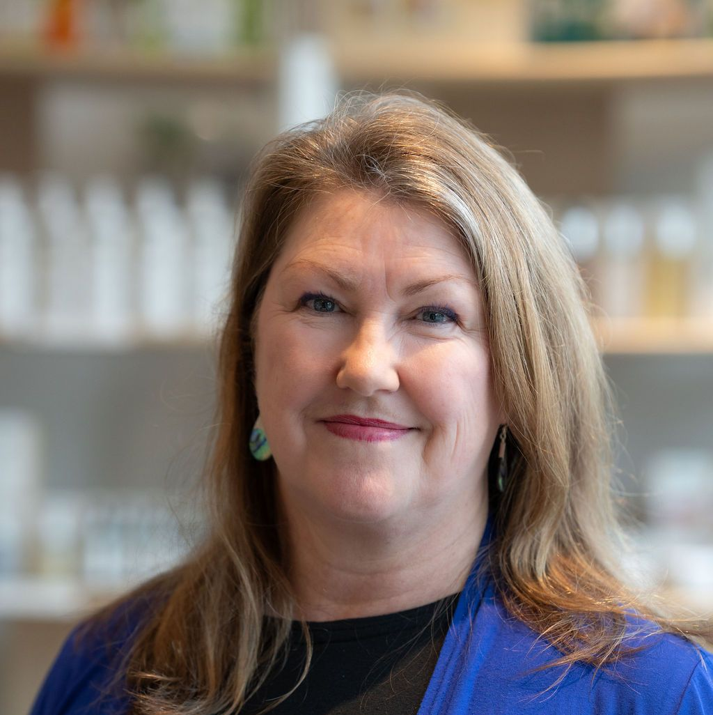 Portrait of a smiling woman in a blue cardigan against a softly blurred indoor background