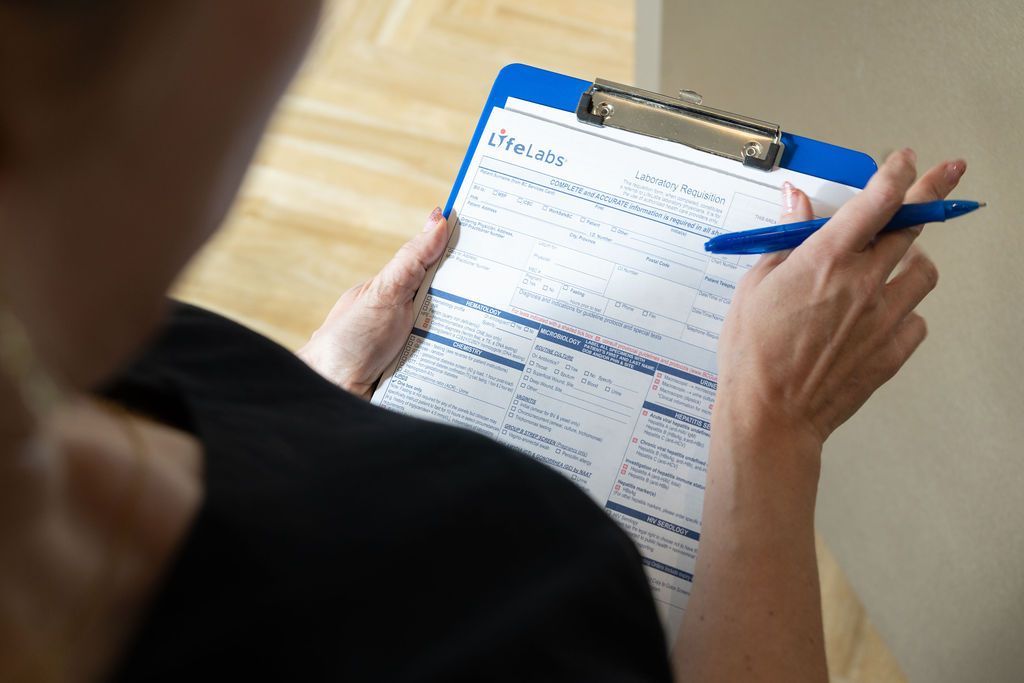 Person writing on a clipboard with a blue pen, filling out a form.