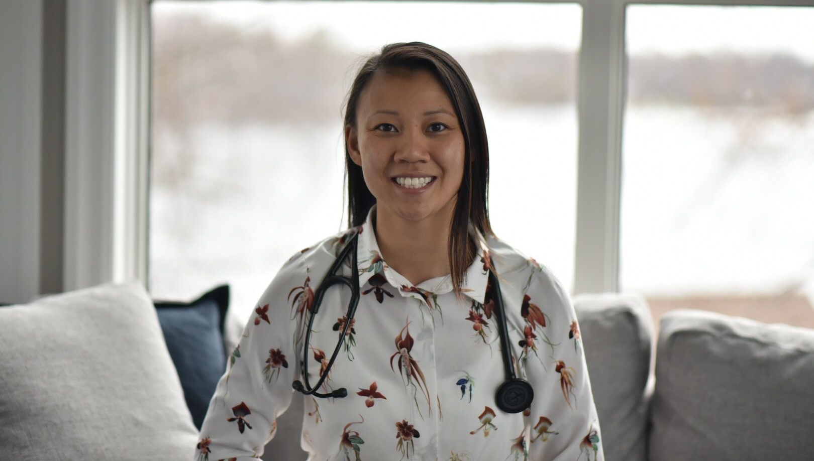 Portrait of a smiling woman in a blue cardigan against a softly blurred indoor background