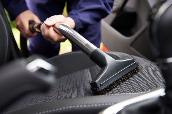 a person is cleaning the seats of a car with a vacuum cleaner .