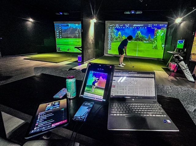 A man is swinging a golf club in a golf simulator.
