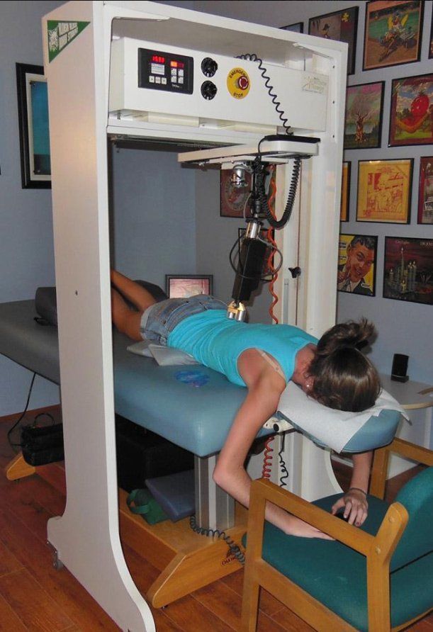 Woman lying on a robotic therapy bed receiving precise, non-invasive lower back treatment.