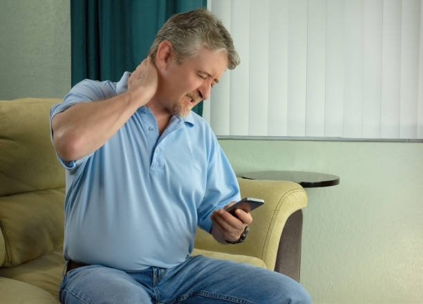 A man is sitting on a couch looking at his cell phone.
