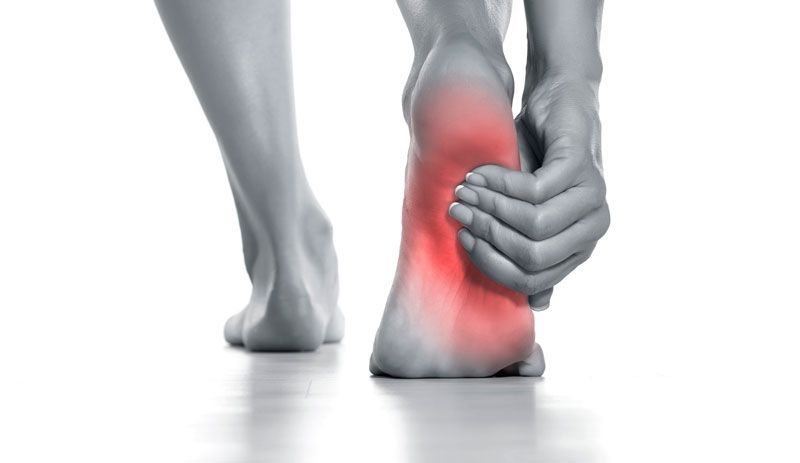 A person is holding their foot in pain.
