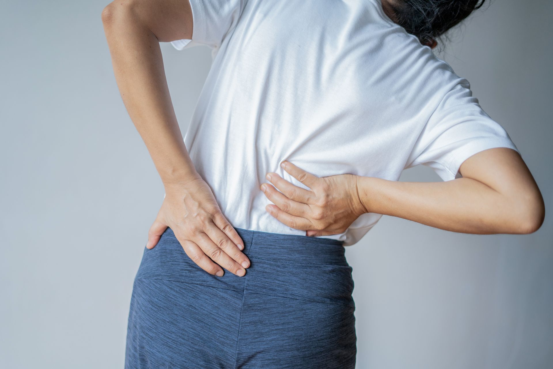 A woman massaging her back muscles due to intense low back pain.
