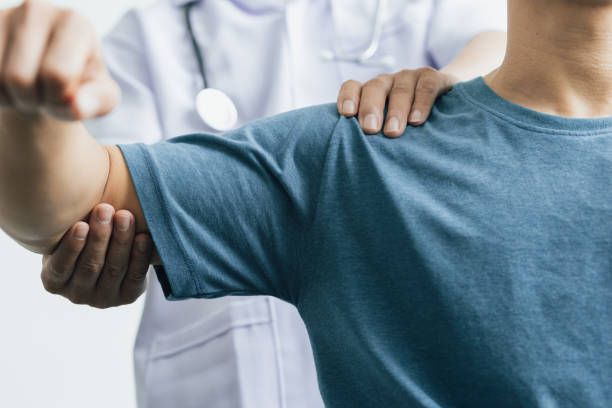 A doctor is examining a patient 's arm and shoulder.