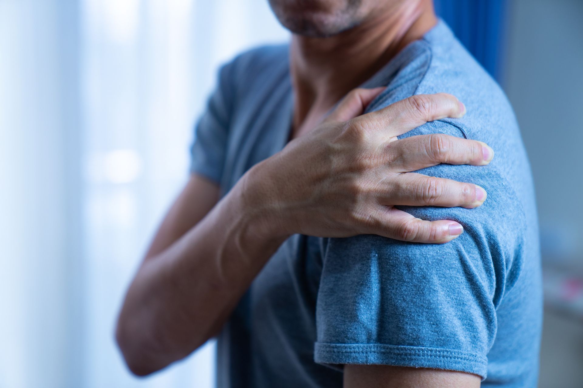 A man is holding his shoulder in pain.