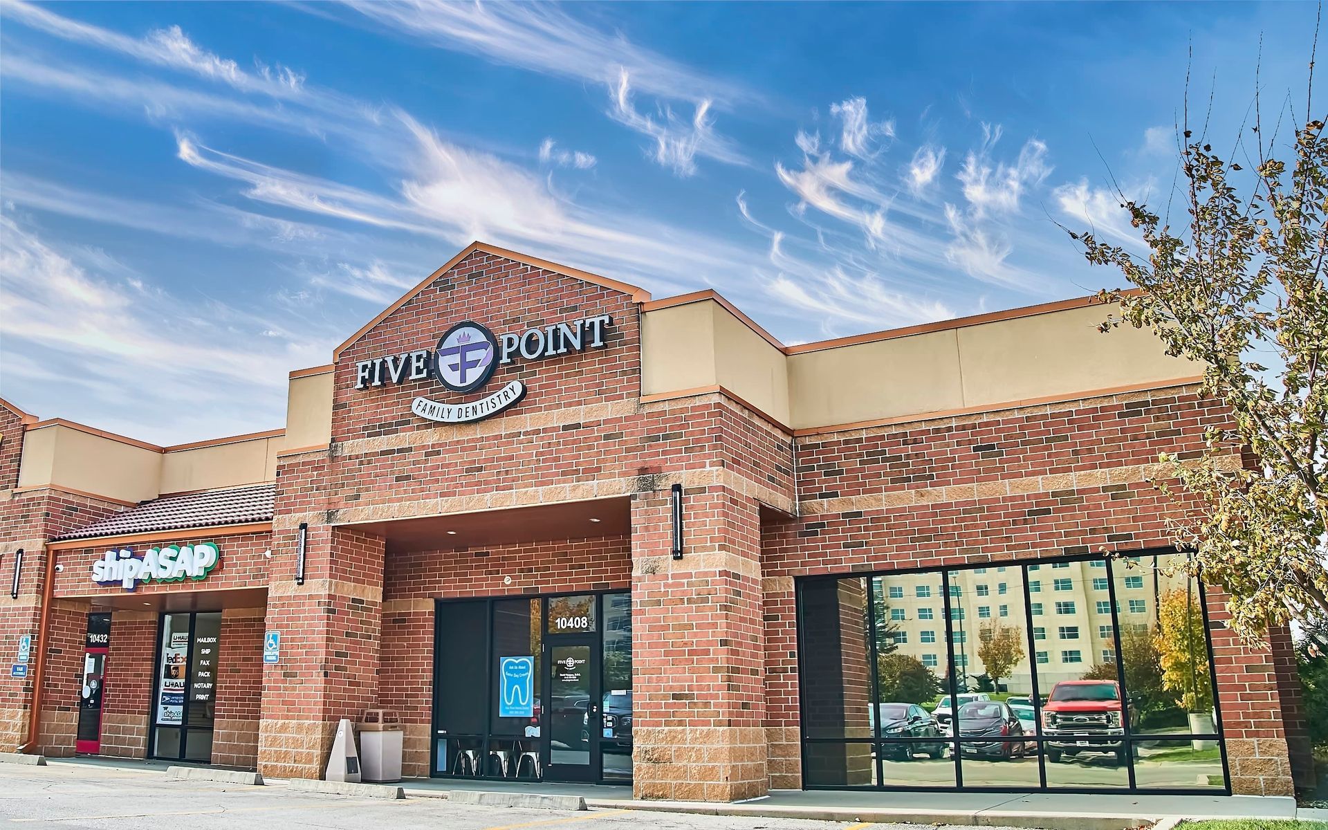 Exterior of Five Point Restaurant, red brick building with blue sky, windows, and surrounding businesses.