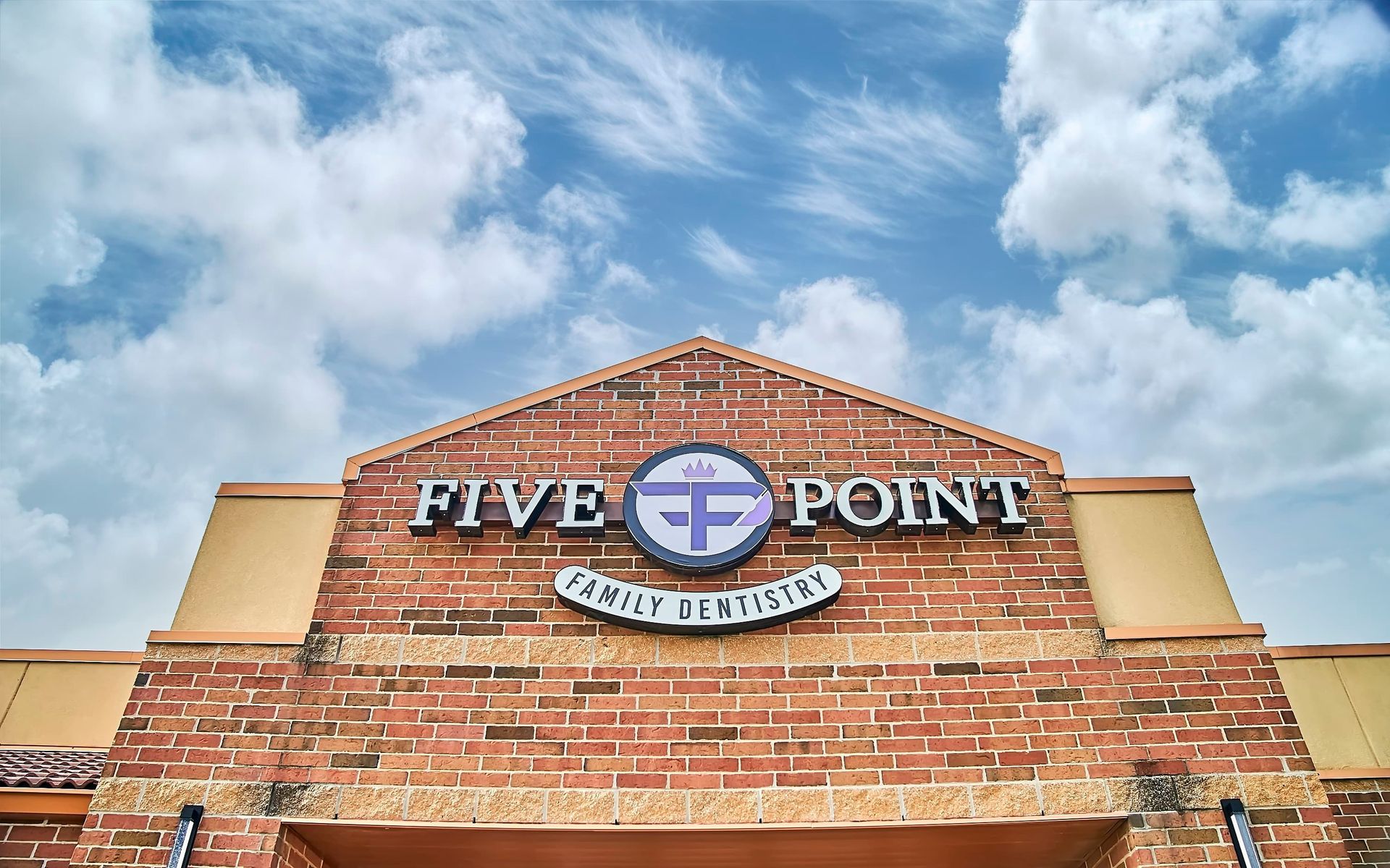Five Point shopping center brick sign against a blue sky with clouds